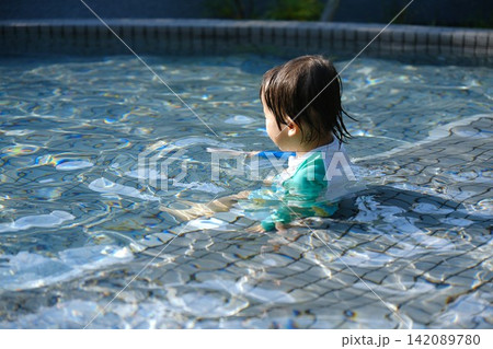 浅いプールに浸かって水遊びをするラッシュガード姿の子供 浅いプールに浸かって水遊びをするラッシュガード姿の子供 142089780
