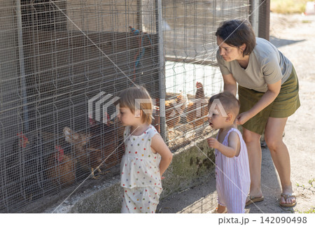 Woman with children near yard with hens Woman with children near yard with hens 142090498