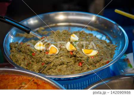 Traditional spicy eggplant salad topped boiled egg red chili served metal tray at local food market featuring authentic Asian cuisine 142090986