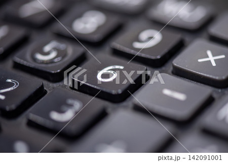 Close up view of black calculator number keys arithmetic symbols highlighting calculation finance accounting mathematics office technology 142091001