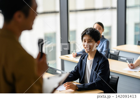 笑顔で講師の話を聞く受講者とビジネスセミナーの風景 笑顔で講師の話を聞く受講者とビジネスセミナーの風景 142091413