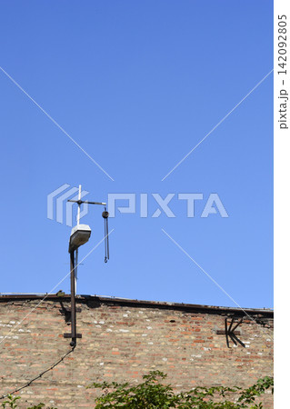 Old brick wall with street lamp and vintage chain hoist pulley Old brick wall with street lamp and vintage chain hoist pulley 142092805