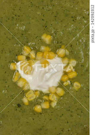 Close up of green zucchini cream soup with corn and sour cream 142092812