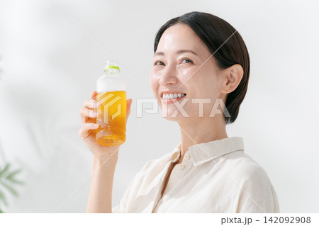 ペットボトルのお茶を飲む笑顔の女性 ペットボトルのお茶を飲む笑顔の女性 142092908