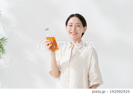 ペットボトルのお茶を飲む笑顔の女性 ペットボトルのお茶を飲む笑顔の女性 142092910
