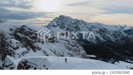 Ski mountaineer crossing a snowy ridge in the Dolomites with dramatic alpine peaks and blue sky in the background, capturing winter adventure and breathtaking mountain landscape. Ski mountaineer crossing a snowy ridge in the Dolomites with dramatic alpine peaks and blue sky in the background, capturing winter adventure and breathtaking mountain landscape. 142092990