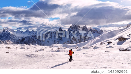 Ski mountaineer crossing a snowy ridge in the Dolomites with dramatic alpine peaks and blue sky in the background, capturing winter adventure and breathtaking mountain landscape. Ski mountaineer crossing a snowy ridge in the Dolomites with dramatic alpine peaks and blue sky in the background, capturing winter adventure and breathtaking mountain landscape. 142092991