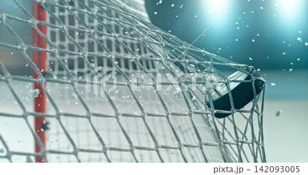 Action sports photo of a hockey puck flying into the goal net during a scoring shot, with ice particles in the air, capturing speed and intensity. Action sports photo of a hockey puck flying into the goal net during a scoring shot, with ice particles in the air, capturing speed and intensity. 142093005