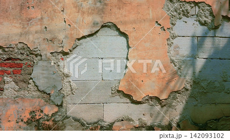 Weathered wall with peeling plaster and exposed concrete blocks. Weathered wall with peeling plaster and exposed concrete blocks. 142093102