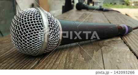 Dynamic vocal microphone on a wooden surface. Dynamic vocal microphone on a wooden surface. 142093266