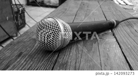 Black and white wired microphones on a rustic wooden table. 142093273