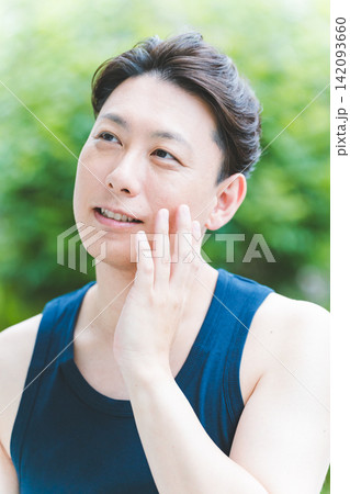 屋外で片手を頬に当て気持ちよさそうに微笑む40代男性のボタニカルフェイスケア 屋外で片手を頬に当て気持ちよさそうに微笑む40代男性のボタニカルフェイスケア 142093660