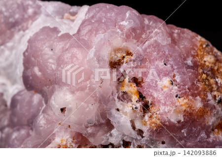 Macro pink Smithsonite mineral stone on microcline on black background Macro pink Smithsonite mineral stone on microcline on black background 142093886