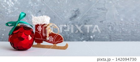Christmas ball with skates on colored background. decoration bauble with ribbon bow with copy space 142094730