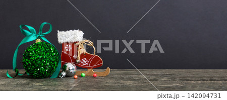 Christmas ball with skates on colored background. decoration bauble with ribbon bow with copy space 142094731