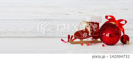 Christmas ball with skates on colored background. decoration bauble with ribbon bow with copy space Christmas ball with skates on colored background. decoration bauble with ribbon bow with copy space 142094732
