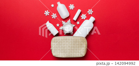 Christmas flat lay with makeup cosmetic products in cosmetic bag on colored background. Top view New year Beauty concept Christmas flat lay with makeup cosmetic products in cosmetic bag on colored background. Top view New year Beauty concept 142094992