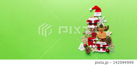 Christmas tree made from colored suit santa decoration on colored background, view from above. New Year minimal concept with copy space Christmas tree made from colored suit santa decoration on colored background, view from above. New Year minimal concept with copy space 142094999