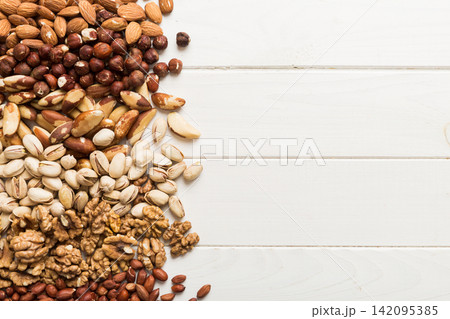 different nuts frame background. Close up, top view, flat lay with vopy space. Walnut, pistachios, almonds, hazelnuts and cashews 142095385