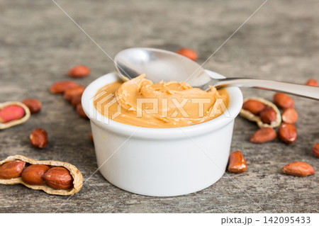 Bowl of peanut butter and peanuts on table background. top view with copy space. Creamy peanut pasta in small bowl 142095433