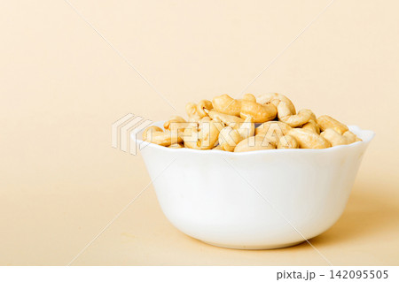 cashew nuts in wooden bowl on table background. top view. Space for text Healthy food cashew nuts in wooden bowl on table background. top view. Space for text Healthy food 142095505