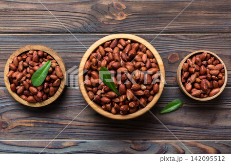 Fresh healthy peanuts in bowl on colored table background. Top view Healthy eating bertholletia concept. Super foods Fresh healthy peanuts in bowl on colored table background. Top view Healthy eating bertholletia concept. Super foods 142095512