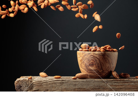 Almond is poured into a wooden bowl. 142096408