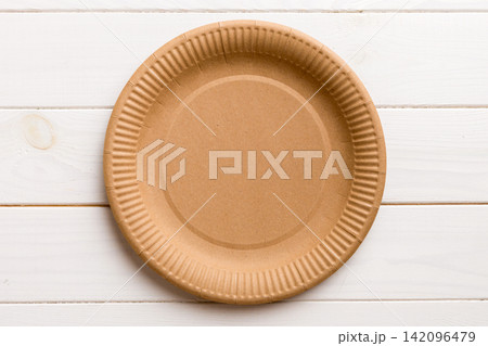 Top view of eco paper plate on wooden background. Empty space for your design Top view of eco paper plate on wooden background. Empty space for your design 142096479