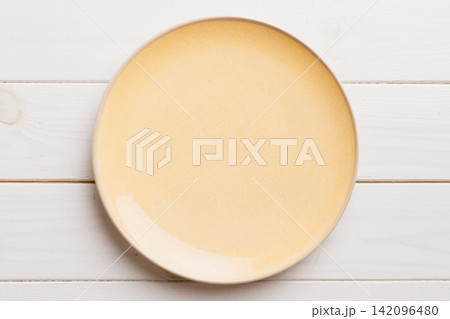 Top view of empty orange plate on wooden background. Empty space for your design Top view of empty orange plate on wooden background. Empty space for your design 142096480