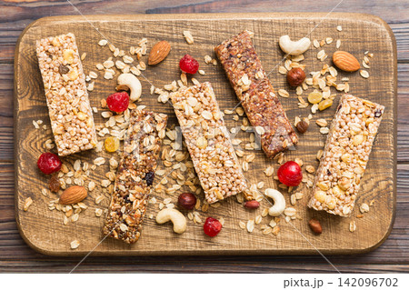 Various granola bars on table background. Cereal granola bars. Superfood breakfast bars with oats, nuts and berries, close up. Superfood concept Various granola bars on table background. Cereal granola bars. Superfood breakfast bars with oats, nuts and berries, close up. Superfood concept 142096702