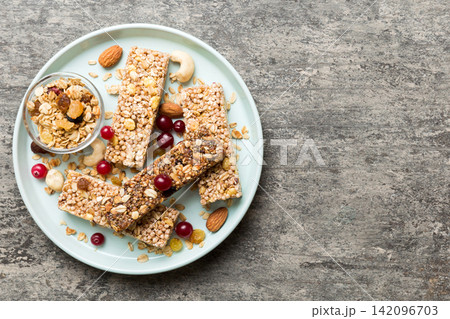 Various granola bars on table background. Cereal granola bars. Superfood breakfast bars with oats, nuts and berries, close up. Superfood concept Various granola bars on table background. Cereal granola bars. Superfood breakfast bars with oats, nuts and berries, close up. Superfood concept 142096703