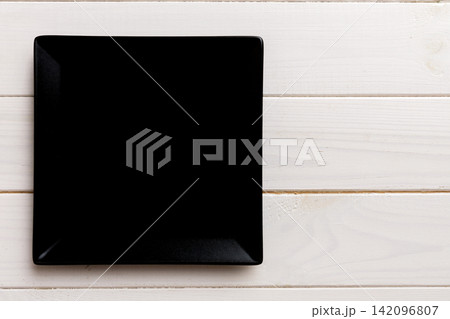Top view of empty square plate on wooden background. Empty space for your design Top view of empty square plate on wooden background. Empty space for your design 142096807