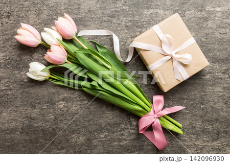 Pink tulips flowers and gift or present box on colored table background. Mothers Day, Birthday, Womens Day, celebration concept. Space for text top view 142096930