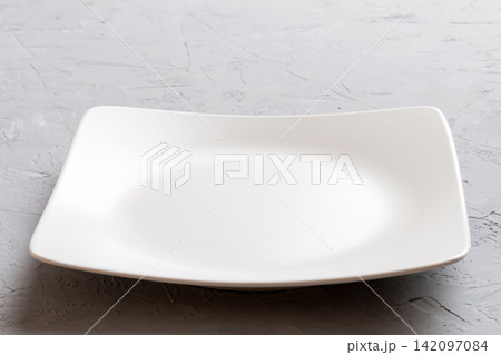 Perspective view of empty square plate on cement background. Empty space for your design Perspective view of empty square plate on cement background. Empty space for your design 142097084