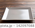 Perspective view of empty square plate on wooden background. Empty space for your design 142097088