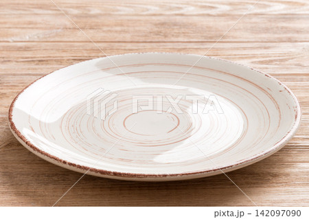 Perspective view of empty colorful plate on wooden background. Empty space for your design 142097090