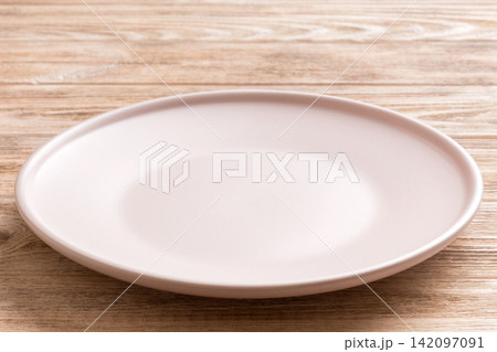 Perspective view of empty light plate on wooden background. Empty space for your design 142097091