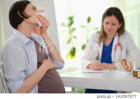 Pregnant woman patient blows nose during clinic appointment Pregnant woman patient blows nose during clinic appointment 142097877