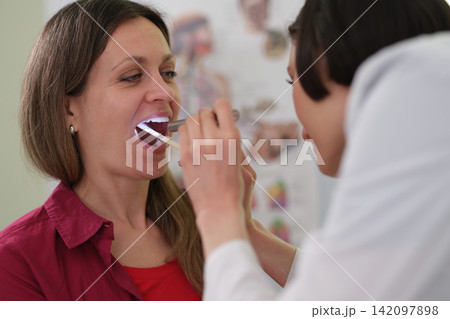 Woman doctor checks patient throat during clinic examination 142097898