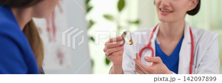Woman doctor explains hearing aid function during clinic visit Woman doctor explains hearing aid function during clinic visit 142097899