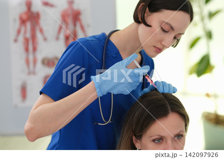 Woman doctor examines patient scalp during clinic appointment Woman doctor examines patient scalp during clinic appointment 142097926