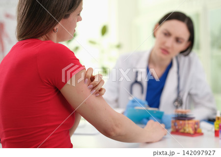 Woman patient shows irritated skin on arm during consultation Woman patient shows irritated skin on arm during consultation 142097927