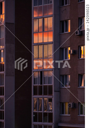 Apartment building windows reflecting glowing sunset sky. Apartment building windows reflecting glowing sunset sky. 142098023