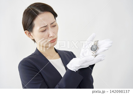 困った顔で腕時計を持つ女性鑑定士 白背景 困った顔で腕時計を持つ女性鑑定士 白背景 142098137