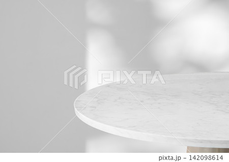 Round marble table top with tree leaves shadow drop on white wall background for mockup product display Round marble table top with tree leaves shadow drop on white wall background for mockup product display 142098614