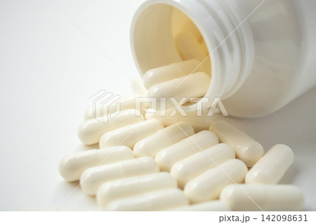 medicine pills capsule spilling out of bottle on white background medicine pills capsule spilling out of bottle on white background 142098631