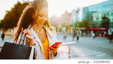 Young woman with shopping bags walking on street. Sale, shopping and happy people concept. 142099405