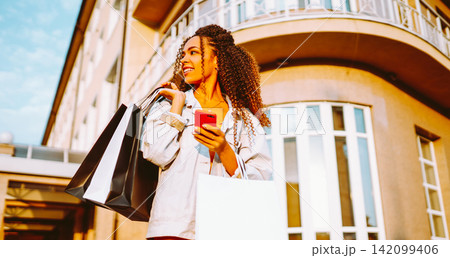 Young woman with shopping bags walking on street. Sale, shopping and happy people concept. 142099406