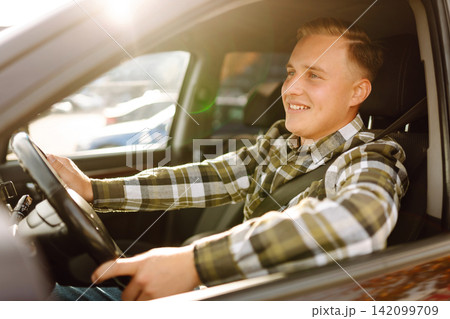 Young man in car smiling and looking at camera. Buying, renting car. Car travel, lifestyle concept. 142099709