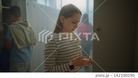 Teenage Girl Enters School Locker Room, Greets Classmates, Places Belongings in Personal Locker Teenage Girl Enters School Locker Room, Greets Classmates, Places Belongings in Personal Locker 142100290